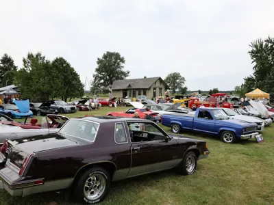 A large group of cars are parked on the Oil Museum grounds during the 2025 Wheels & Wells car show.