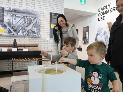Children practice dipping candles at the Oil Museum of Canada.